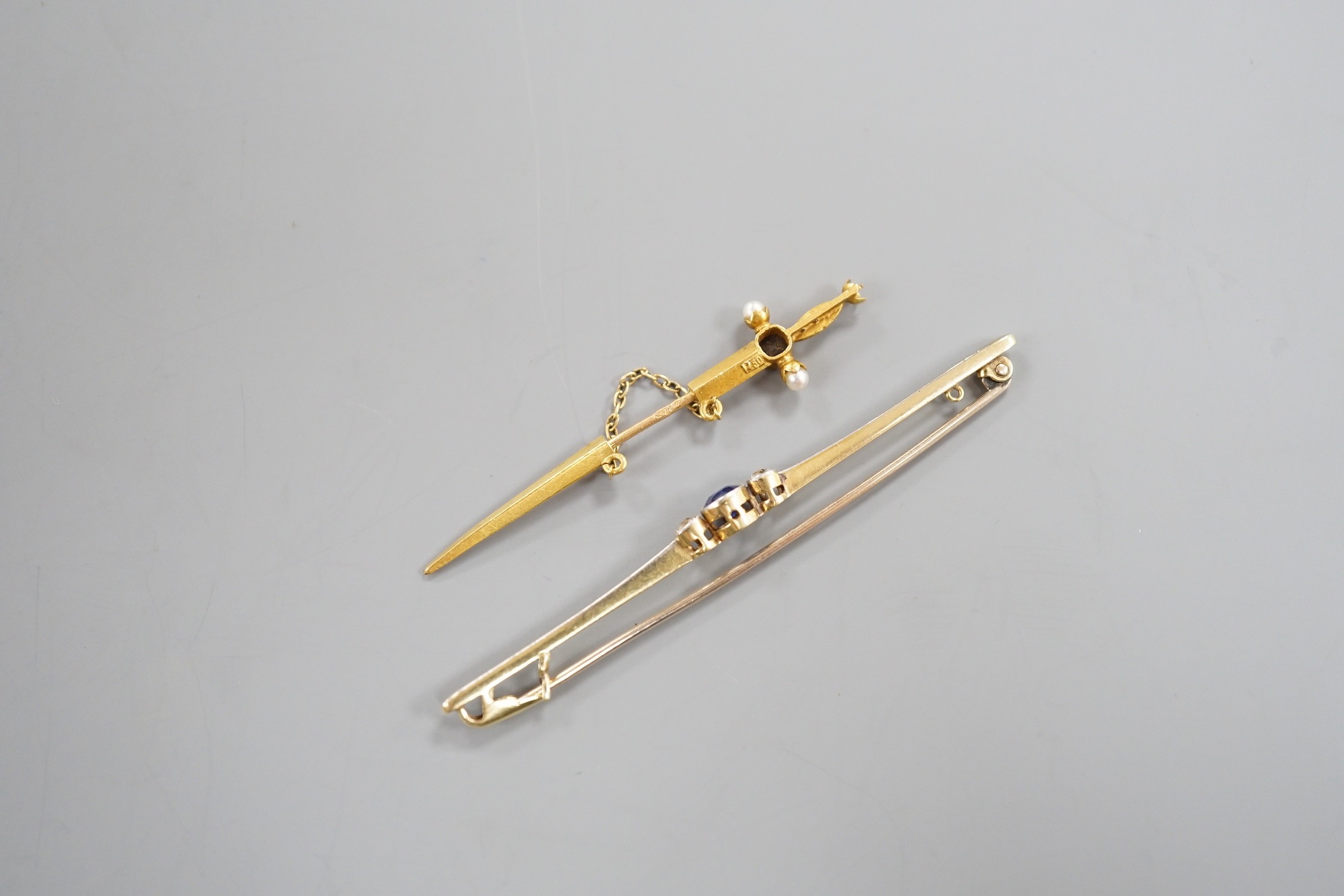 An early 20th French yellow metal (18ct poincon mark), sapphire and seed pearl set jabot pin, modelled a sword, 49mm, gross 1.3 grams and an Edwardian 15ct, sapphire and diamond set bar brooch, gross weight 3.2 grams.